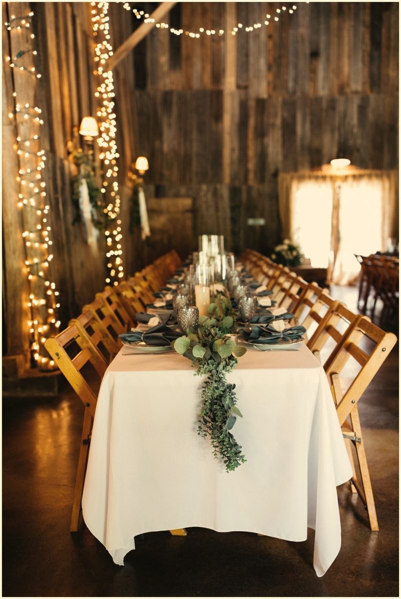 Greenery chandelier hanging over dinner tables in the barn