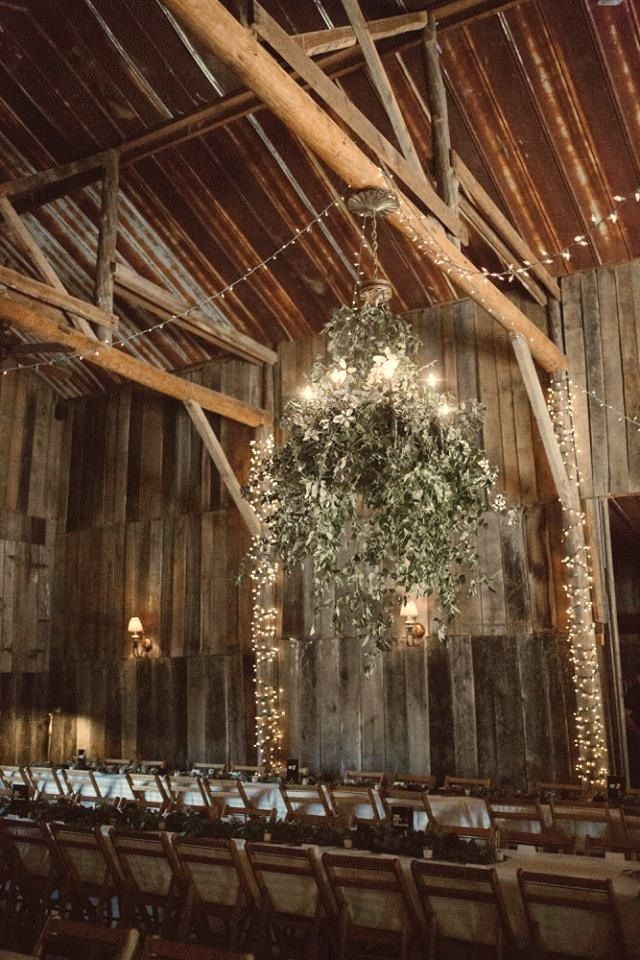 Long table with white linen and greenery in the candlelit barn