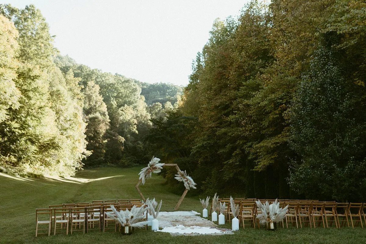 Guests seated on the grass for a ceremony in the wooded cove
