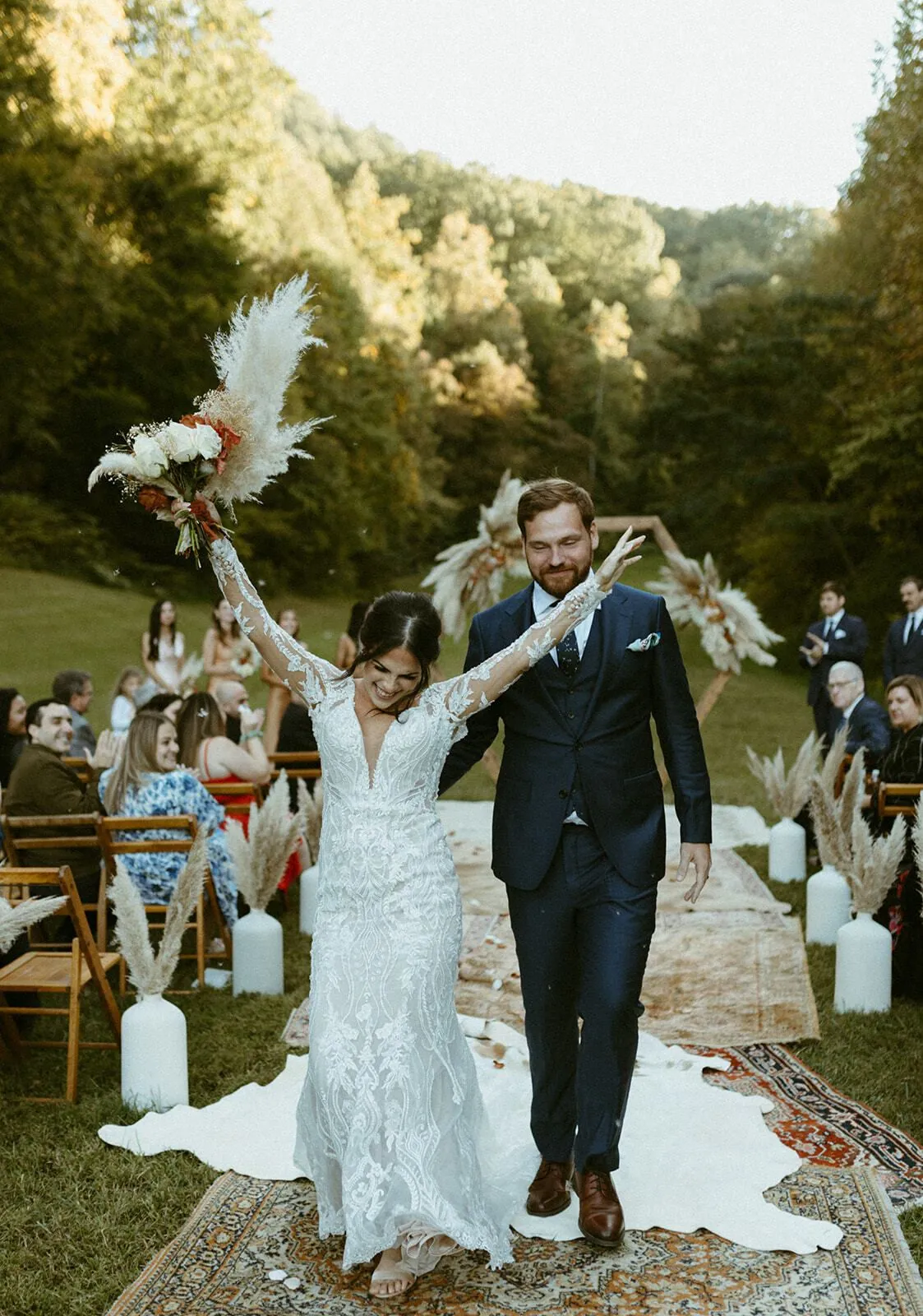A couple walking back up the aisle in the wooded cove